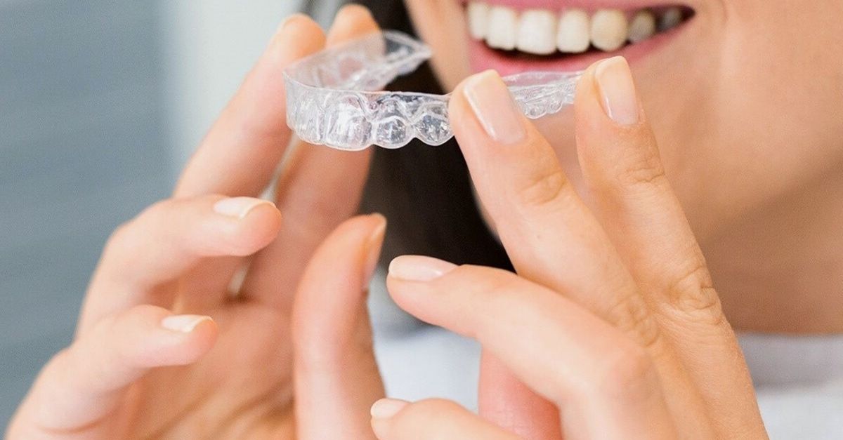 Alineador dental transparente sostenido entre los dedos